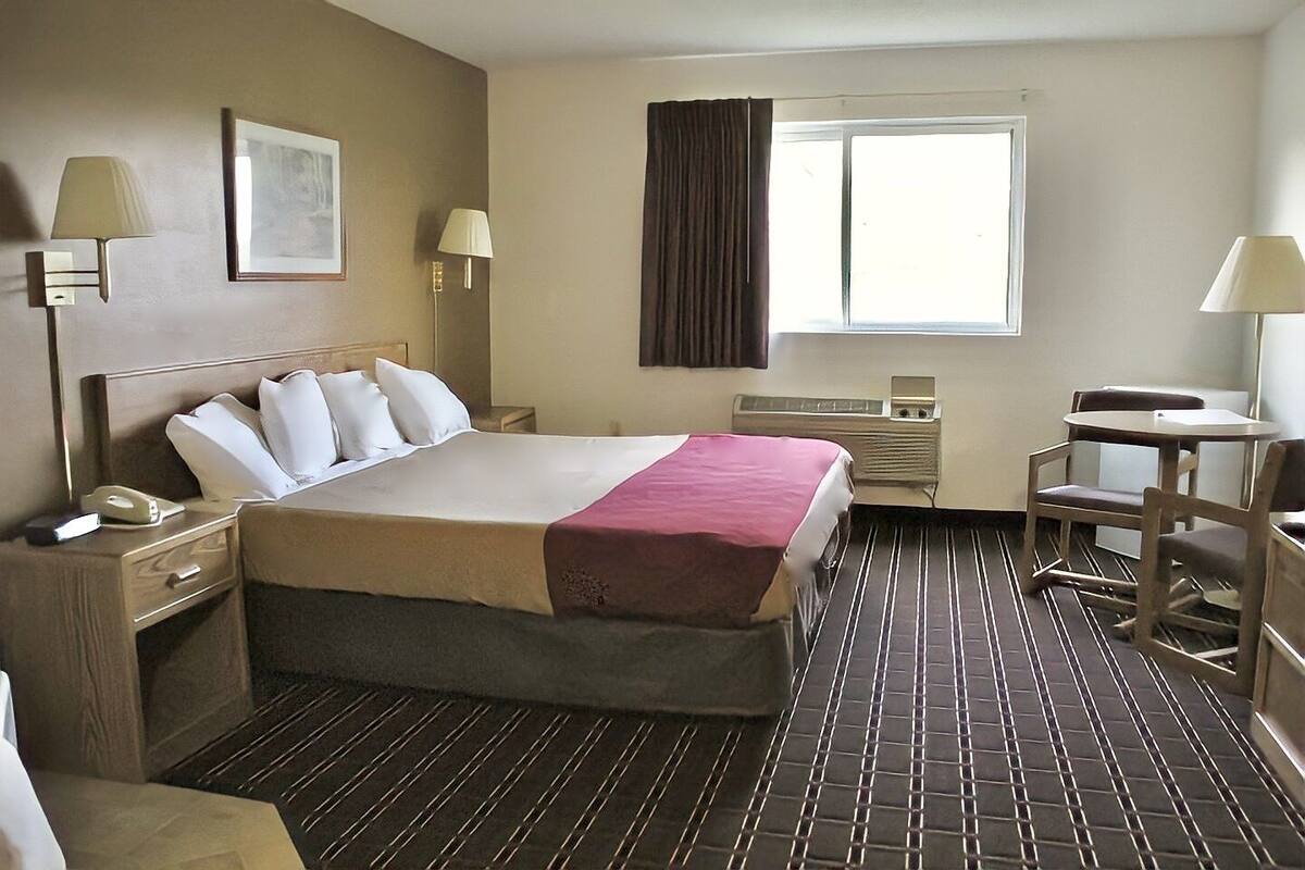 A hotel room with a bed, bedside tables, a desk, and a chair.