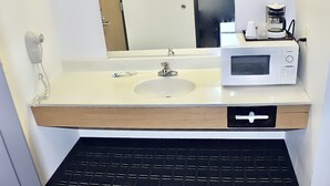 A bathroom with a sink, a mirror, a microwave, and a coffee maker. - AmeriVu Inn and Suites - Stanley (Stanley)