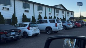 A parking lot with several cars parked in front of a building with a sign that reads "AmeriVu Inn & Suites." - AmeriVu Inn and Suites - Stanley (Stanley)