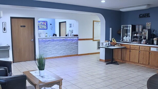 A hotel lobby with a reception desk, a coffee station, and a seating area with a plant. - AmeriVu Inn and Suites - Stanley (Stanley)