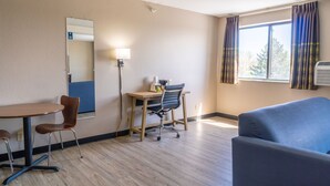 A hotel room with a desk, chair, and couch. - Super 8 by Wyndham Sioux City South (Sioux City)