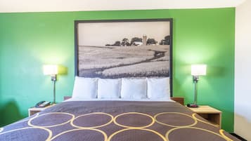 A hotel room with a bed, green walls, a large landscape painting, two bedside lamps, and a telephone on the nightstand.