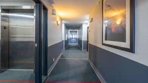 A hotel corridor with an elevator, a framed picture on the wall, and a carpeted floor. - Super 8 by Wyndham Sioux City South (Sioux City)