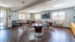 A spacious room with a large dining table, multiple chairs, a sofa, and a television. - Super 8 by Wyndham Sioux City South (Sioux City)