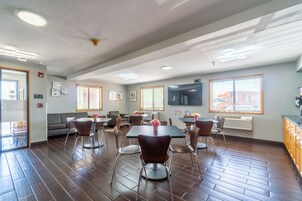A spacious room with a large dining table, multiple chairs, a sofa, and a television.