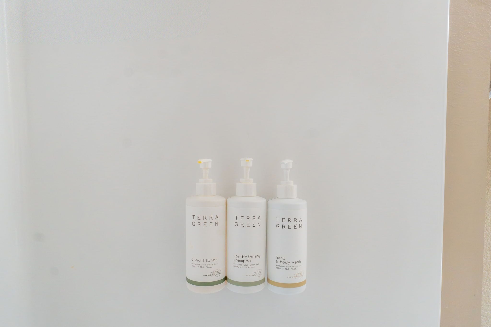Drei Flaschen Terra Green Produkte vor einer schlichten Wand.