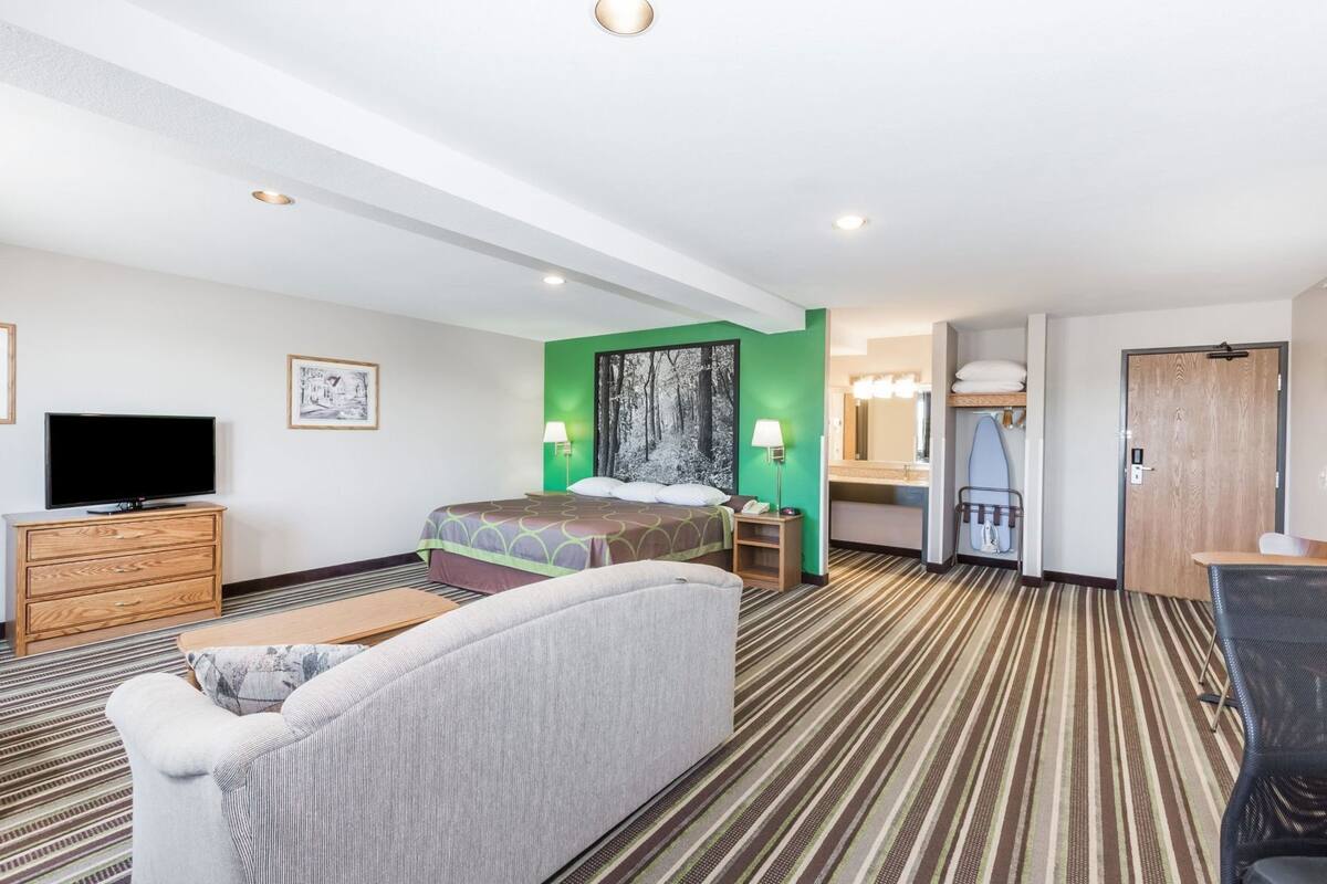 Habitación de hotel con cama, televisión, escritorio, silla, cómoda y baño.