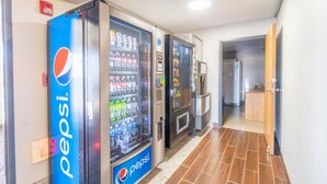 A hallway with vending machines, including a Pepsi machine, and a reception area with a wooden desk. - Super 8 by Wyndham Sioux City South (Sioux City)