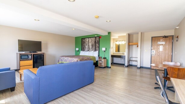 A hotel room with a bed, a sofa, a desk, a TV, a microwave, and a small kitchenette. - Super 8 by Wyndham Sioux City South (Sioux City)