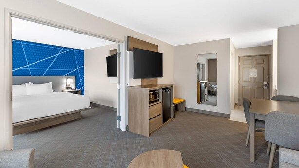 A modern hotel room with a bed, desk, TV, and a dining area. - Comfort Inn & Suites Summerset - North Rapid City (Blackhawk)