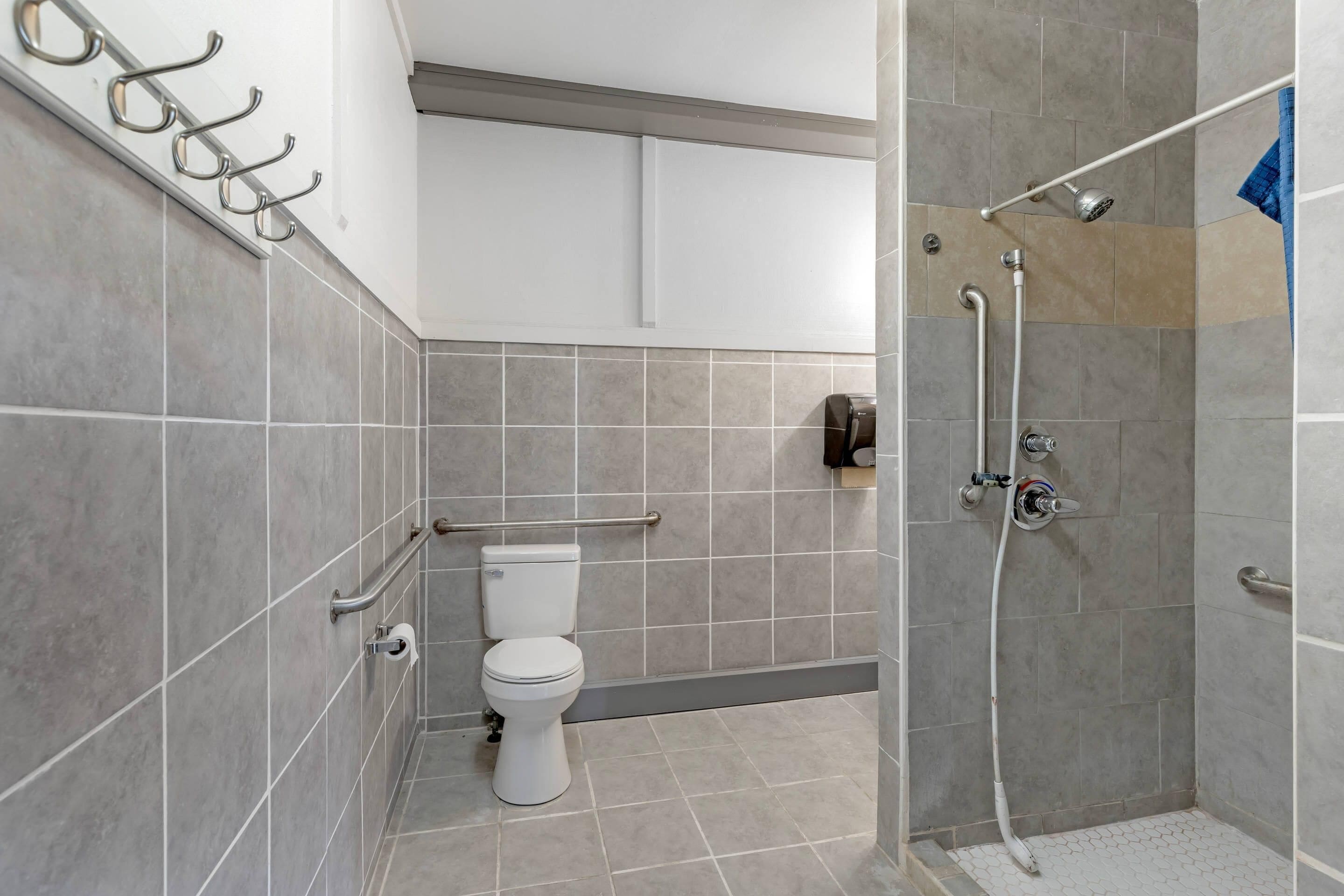 Un baño con inodoro, ducha y toallero.