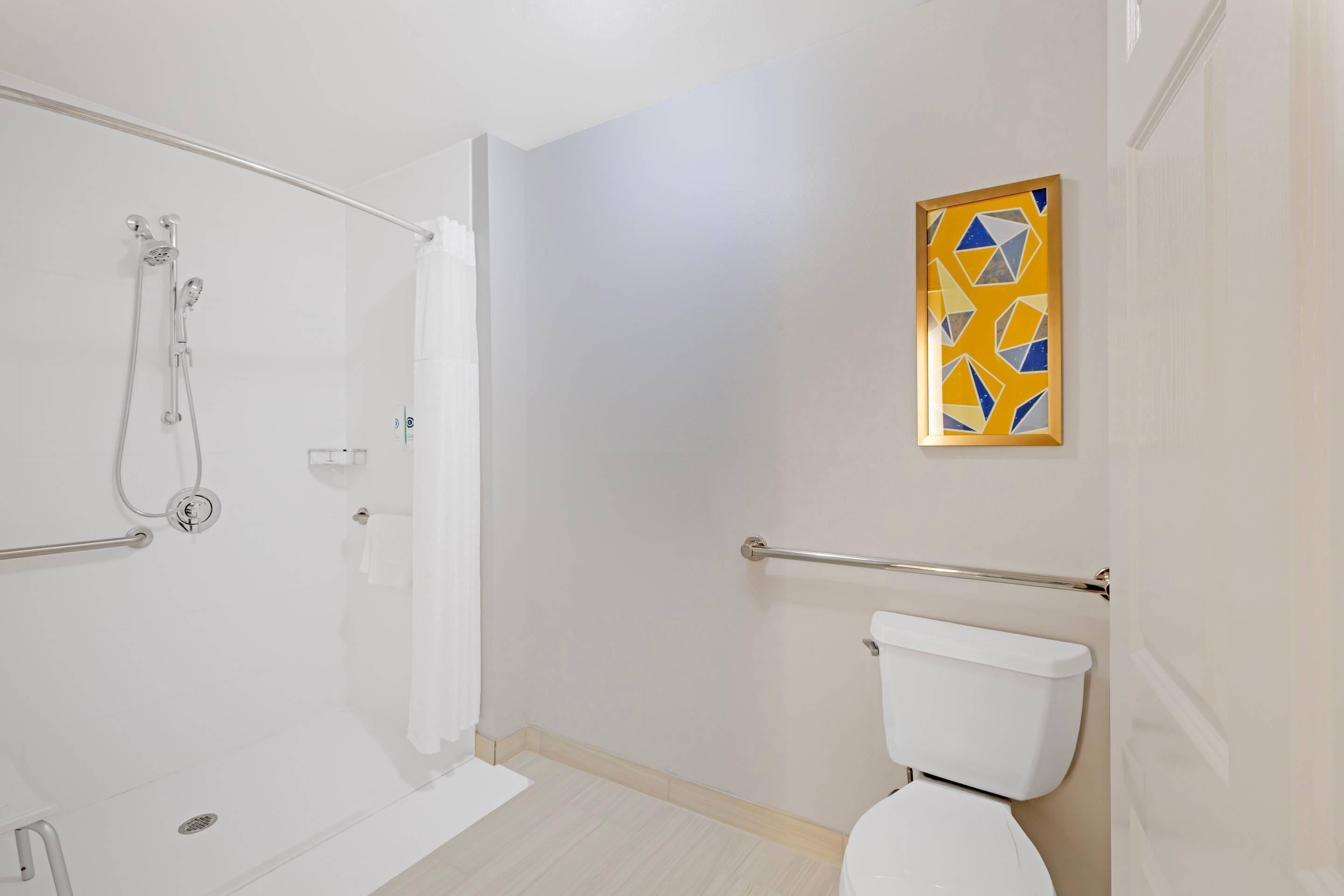 Une salle de bain équipée d’une douche, de toilettes et d’une barre d’appui.