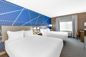 A hotel room with two beds, a desk, a chair, a lamp, and a large window with curtains. - Comfort Inn & Suites Summerset - North Rapid City (Blackhawk)
