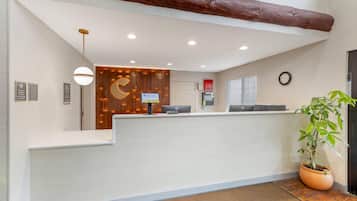Un mostrador de recepción con un panel de madera, un reloj y una planta en maceta.