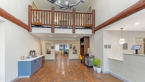 A spacious lobby with a wooden floor, a reception desk, a seating area, and a mezzanine level with a balcony. - Comfort Inn & Suites Summerset - North Rapid City (Blackhawk)