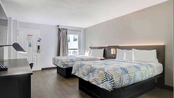 Una habitación de hotel con cama, mesitas de noche, escritorio y ventana con cortinas.