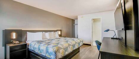 A modern hotel room with a bed, bedside tables, a desk, and a TV.