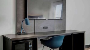 Une chambre d’hôtel moderne équipée d’un téléviseur à écran plat fixé au mur, d’un bureau avec une lampe et d’un four à micro-ondes placé en dessous.