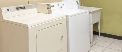 A laundry area with two white Maytag washers and a small white table with a sink.