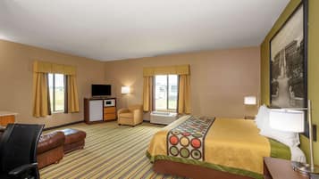 A hotel room with a bed, a desk, a chair, an ottoman, a television, and a painting on the wall.