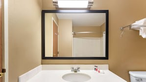 Un baño con lavamanos blanco, un espejo y un inodoro.