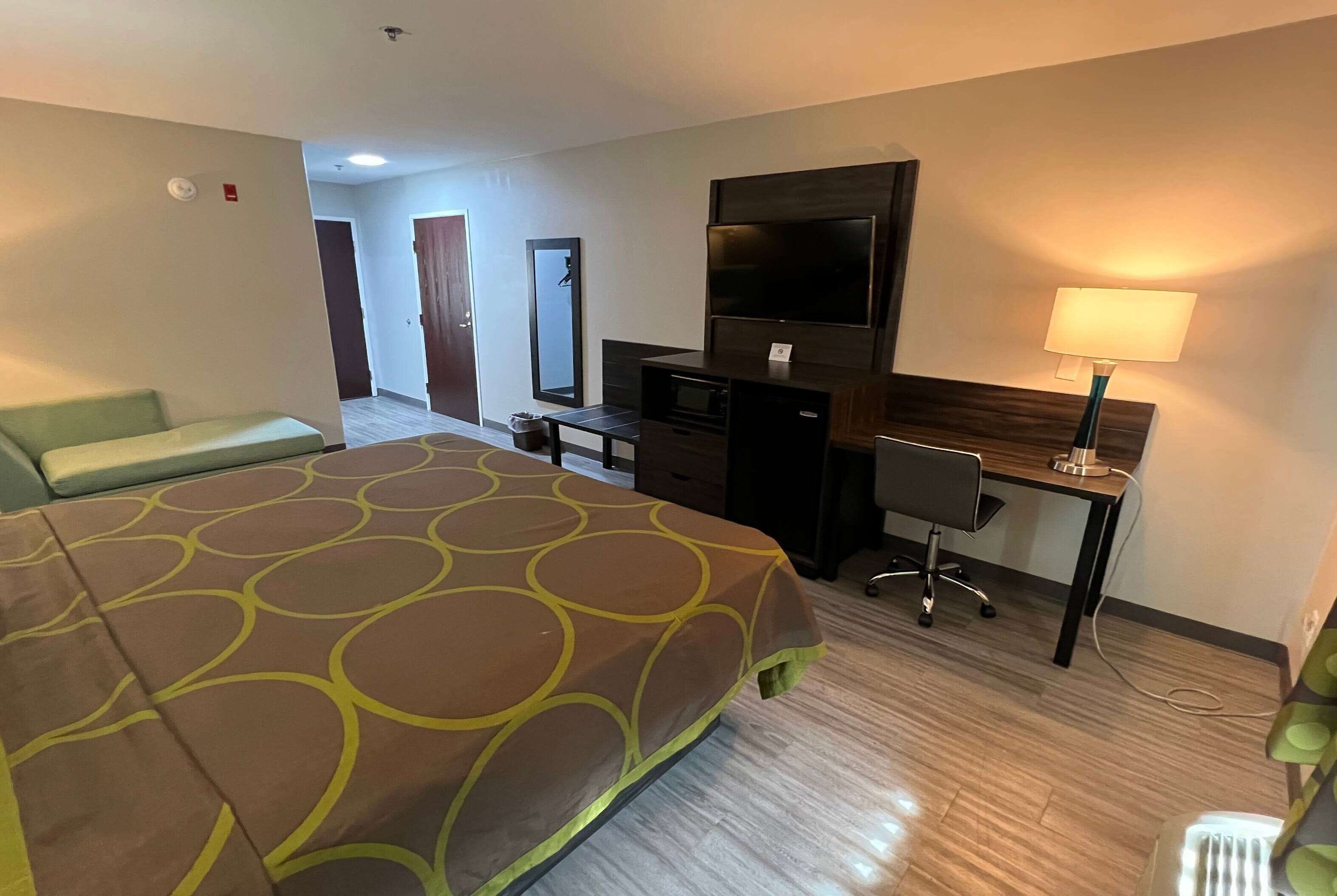 Une chambre d’hôtel avec un lit, un bureau, une télévision et une lampe.