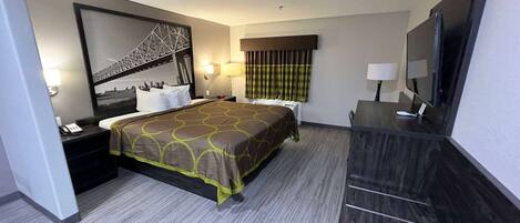 A hotel room with a bed, a desk, a chair, a TV, and a large window.