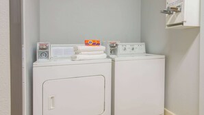 Zona de lavandería con dos lavadoras de carga frontal y una caja de detergente Tide en la lavadora de la izquierda.