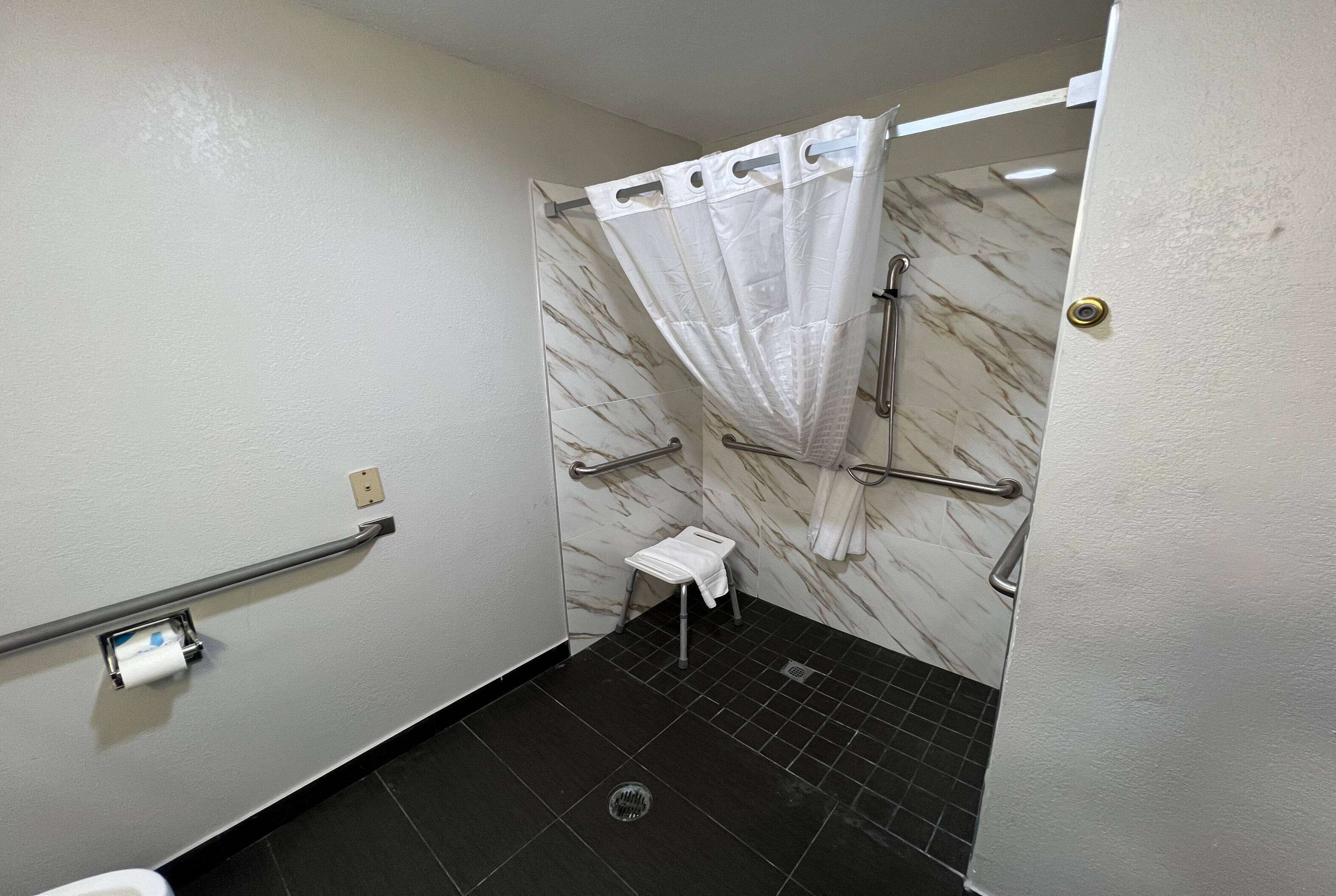 Ein Badezimmer mit Dusche, Toilette und einem kleinen Hocker.
