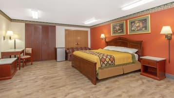 Quarto com cama de madeira, escrivaninha, cadeira e duas luminárias fixadas na parede.