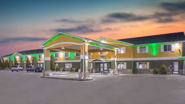 A hotel with a covered entrance, multiple parking spaces, and a landscaped area with trees. - Super 8 by Wyndham Bedford (Bedford)