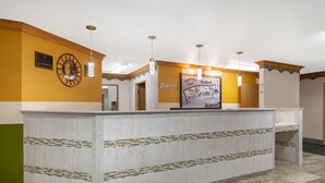A reception area with a marble counter, a welcome sign, a clock, and a framed welcome poster. - Super 8 by Wyndham Bedford (Bedford)