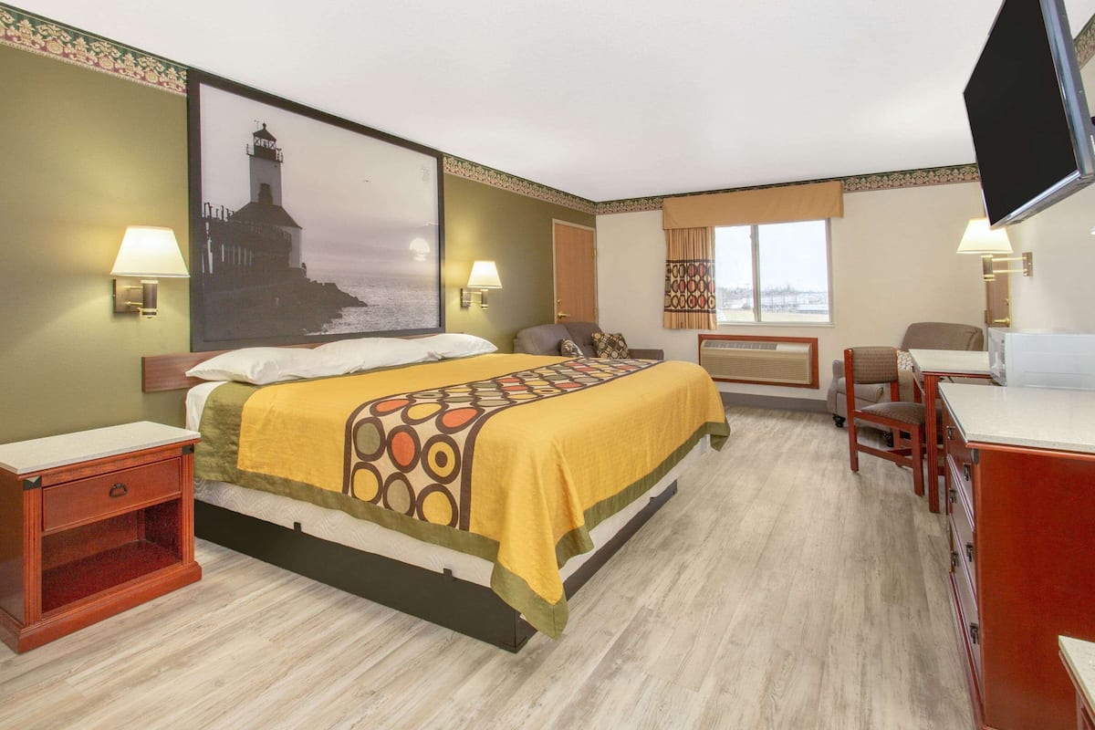 Een hotelkamer met een bed, nachtkastjes, een bureau, een stoel, een televisie en een raam met uitzicht.
