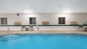 A swimming pool with a clear blue water, a ladder, and chairs along the side. - Super 8 by Wyndham Bedford (Bedford)