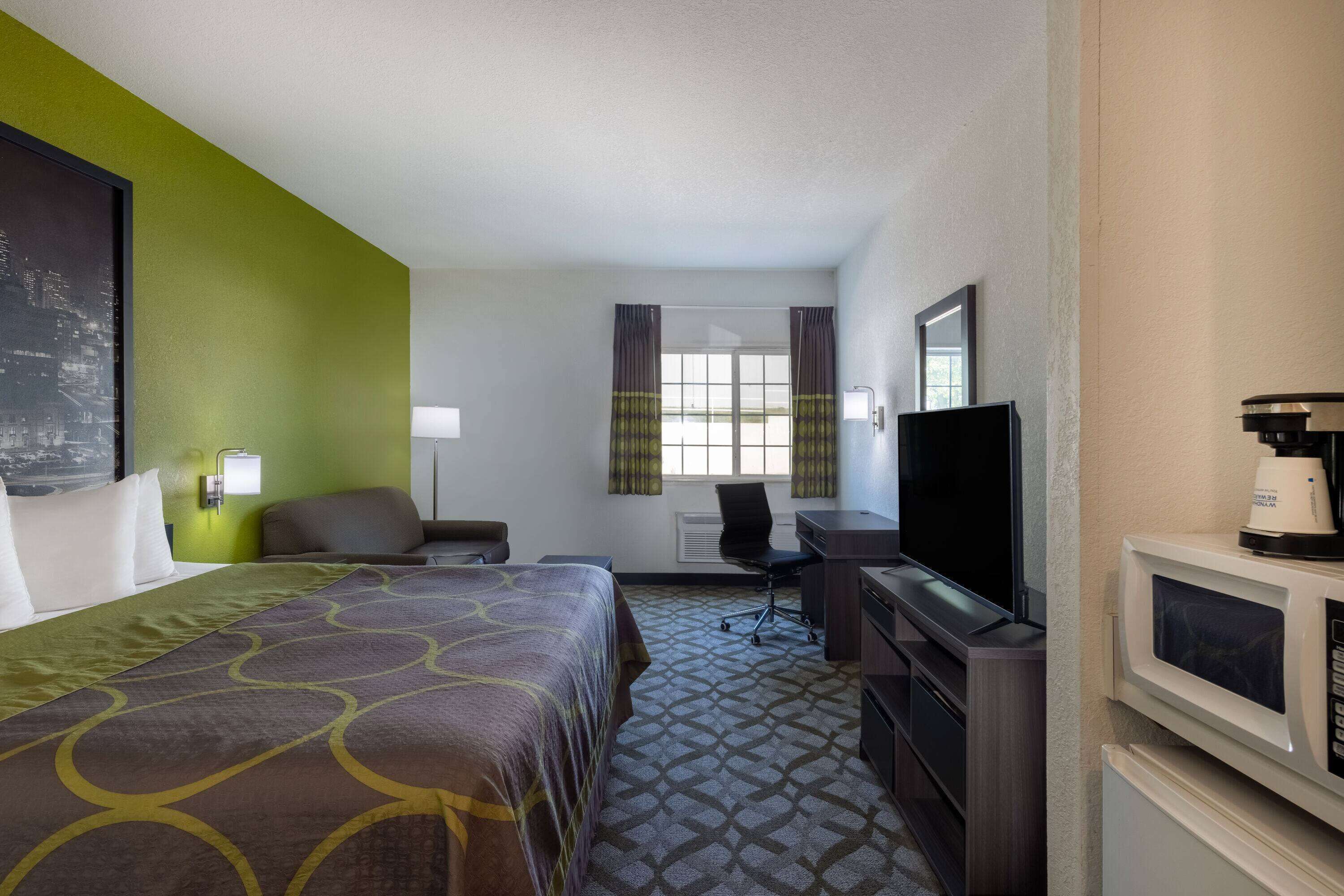 Una habitación de hotel con cama, escritorio, televisión y microondas.