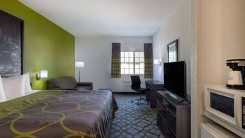 Una habitación de hotel con cama, escritorio, televisión y microondas.