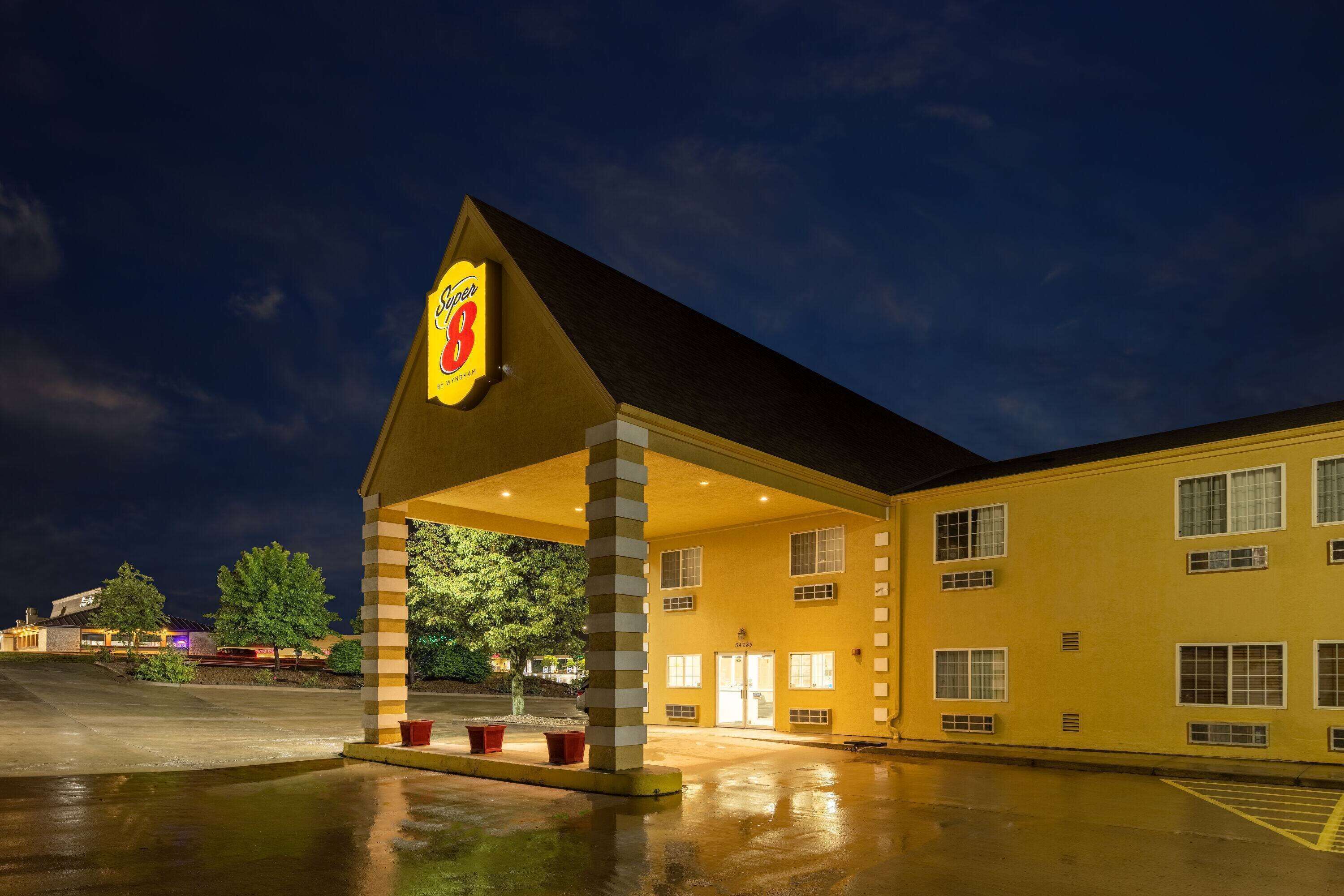 Un motel con un llamativo letrero de 'Super 8', un acceso cubierto y un estacionamiento.