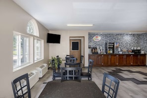 Una cocina moderna con salpicadero de piedra, una zona de comedor con mesa y sillas, y un televisor montado en la pared.