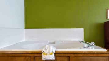 Un baño con una bañera blanca, paredes verdes y muebles de madera.