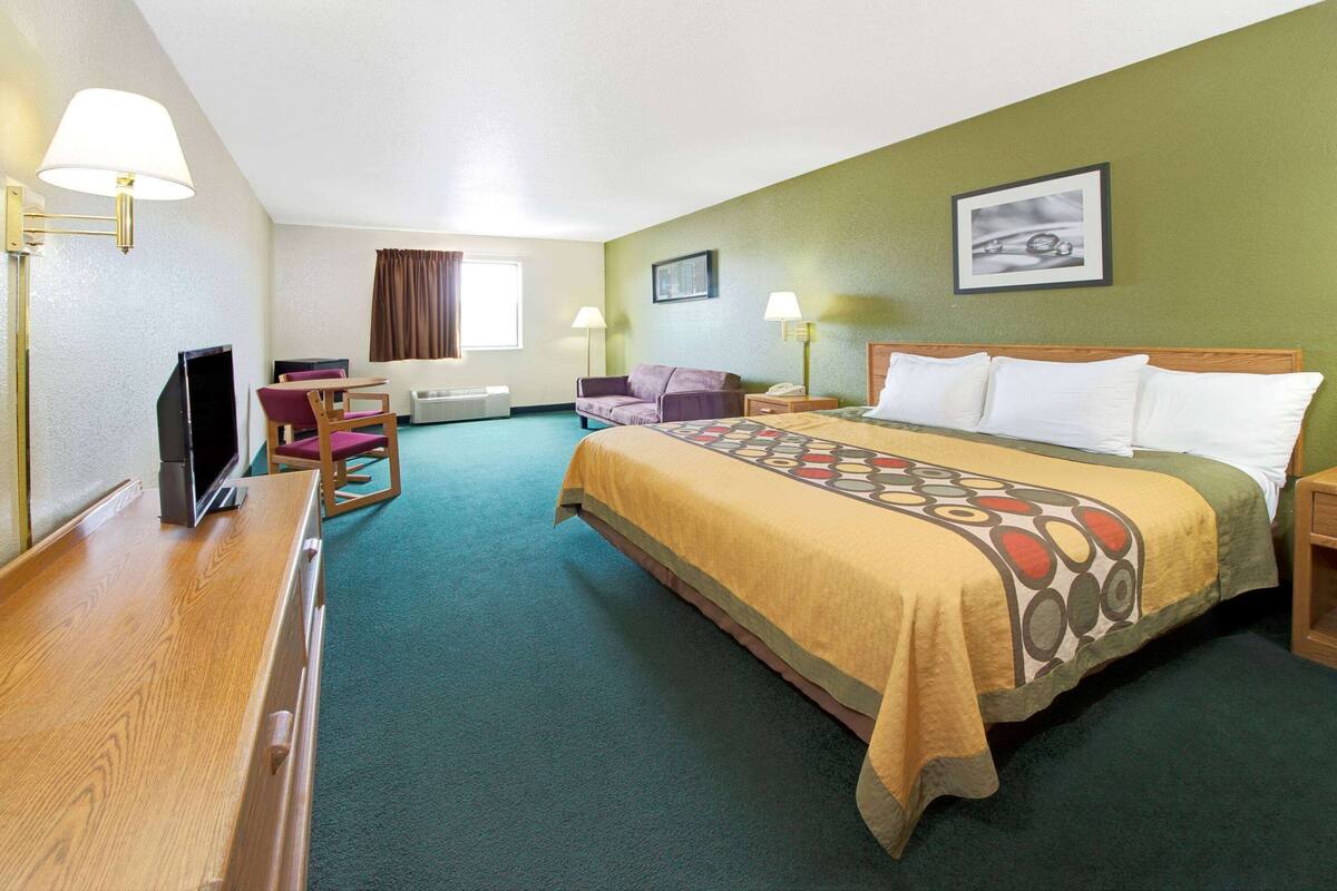 Une chambre d’hôtel équipée d’un lit, d’un bureau, d’une chaise, d’un canapé et d’une télévision.