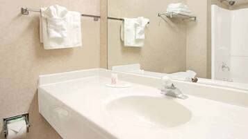 Un baño moderno con un lavamanos grande de color blanco, un espejo y dos toalleros con toallas dobladas con esmero.