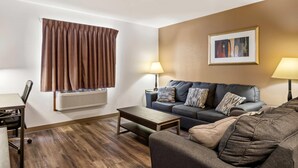A modern living room with a sofa, a coffee table, and a dining area with chairs. - Econo Lodge Inn & Suites Auburn (Auburn)