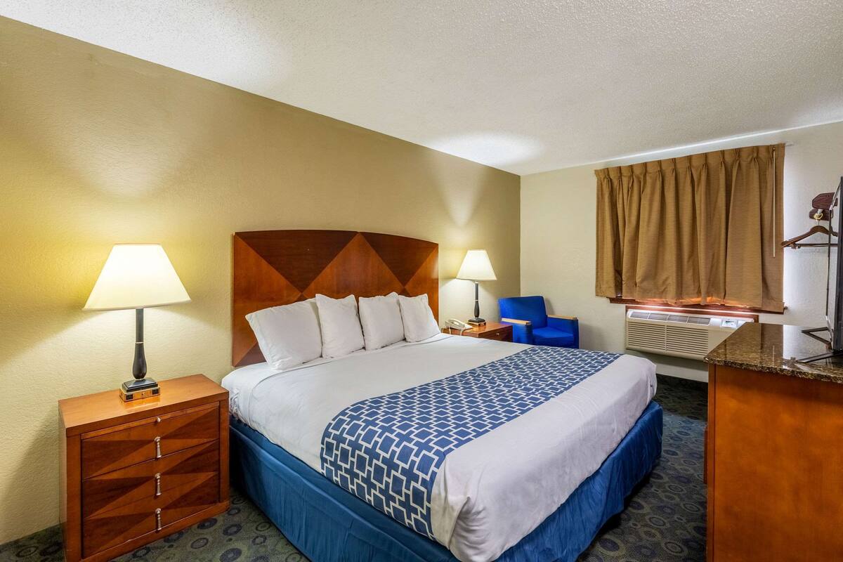 A hotel room with a bed, two bedside tables with lamps, a desk, and a chair.