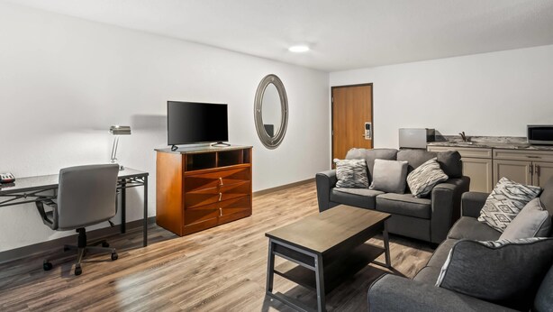 A modern living room with a sofa, coffee table, TV, and wooden cabinet. - Econo Lodge Inn & Suites Auburn (Auburn)