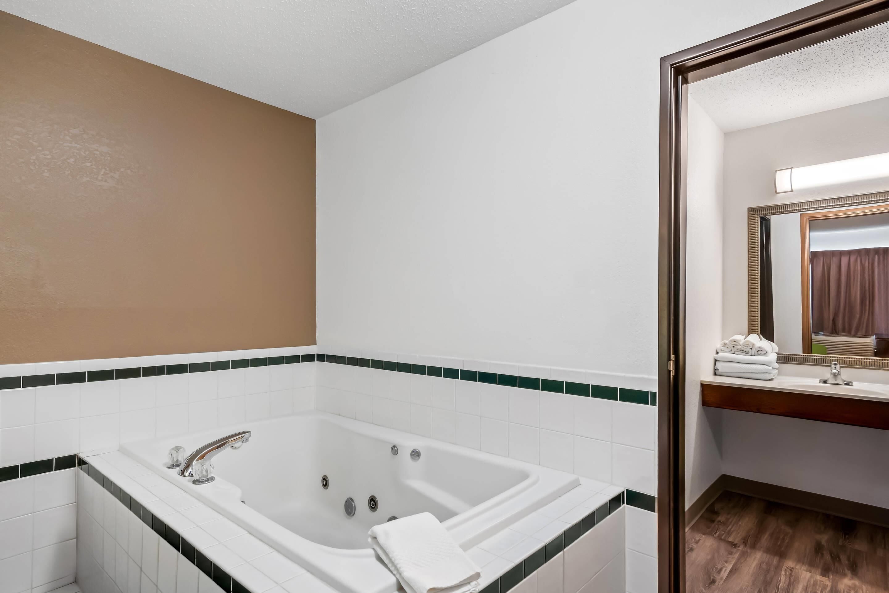 Un baño con una bañera grande, un espejo y un lavamanos.