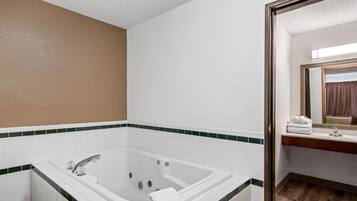 Un baño con una bañera grande, un espejo y un lavamanos.