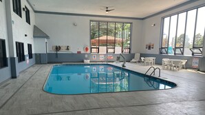 Una piscina interior con suelo de baldosas, un trampolín y señalización de seguridad.