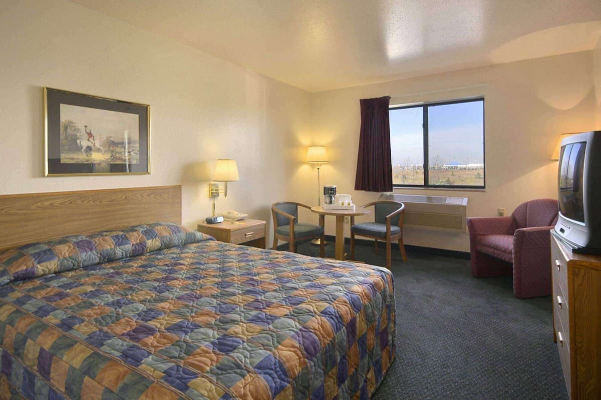 A hotel room with a large bed, a desk with a chair, a television, and a window with a view.