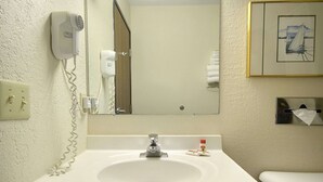 A bathroom with a sink, mirror, hair dryer, and towel rack.