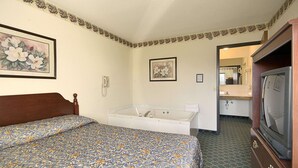 A hotel room with a bed, a bathtub, a television, and a bathroom.
